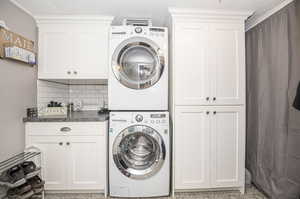 Laundry area featuring stackable washer and clothes dryer (also included), and built in cabinets.