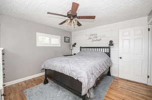 Bedroom #2 with shiplap accent wall, ceiling fan and wood flooring.