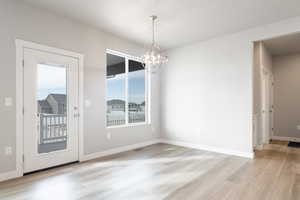 Unfurnished dining area with a chandelier and light hardwood / wood-style floors