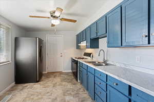 Kitchen with sink, light tile patterned floors, stainless steel refrigerator, black range with gas cooktop, and ceiling fan