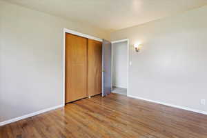 Unfurnished bedroom with a closet and hardwood / wood-style floors