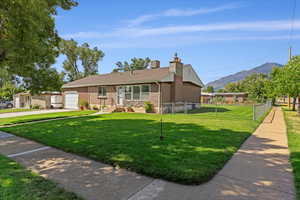 Ranch-style home featuring a front lawn, a mountain view, and a garage