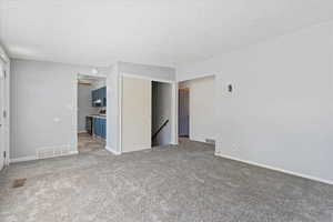 Interior space with light colored carpet and a textured ceiling