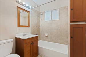 Full bathroom featuring toilet, tiled shower / bath, and vanity