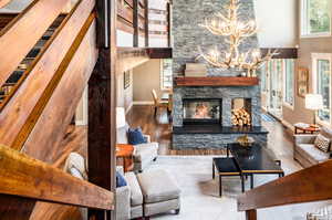 Living room featuring a high ceiling, hardwood / wood-style floors, a stone fireplace, and a chandelier