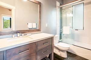 Full bathroom with shower / bath combination with glass door, toilet, and vanity