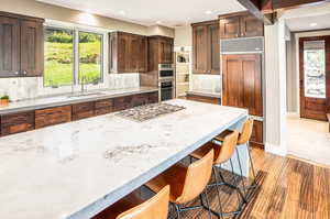 Kitchen with backsplash, appliances with stainless steel finishes, a kitchen bar, sink, and light wood-type flooring