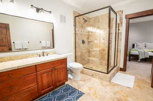 Bathroom featuring toilet, vanity, walk in shower, and tile patterned floors