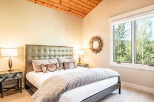 Bedroom featuring wooden ceiling, vaulted ceiling, and light colored carpet