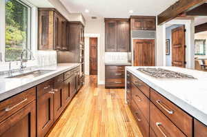 Kitchen with light hardwood / wood-style floors, backsplash, sink, and stainless steel appliances