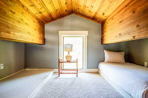 Bedroom with wood ceiling, light colored carpet, and lofted ceiling