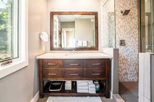 Bathroom featuring a tile shower and vanity