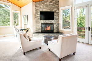 Carpeted living room with wood ceiling, vaulted ceiling, french doors, and a fireplace