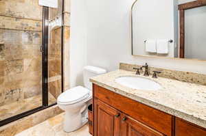 Bathroom featuring tile patterned floors, vanity, walk in shower, and toilet