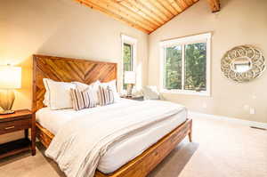 Bedroom with vaulted ceiling, wood ceiling, and carpet flooring