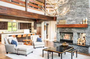 Living room featuring a fireplace, light hardwood / wood-style flooring, a notable chandelier, and a high ceiling