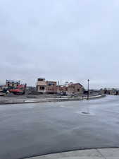 View of asphalt street featuring sidewalks, street lights, and curbs