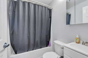 Full bathroom with vanity, shower / tub combo with curtain, and toilet