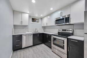 Kitchen with stainless steel appliances, light hardwood / wood-style flooring, and white cabinets