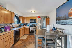 Kitchen with sink, dark tile patterned floors, and black appliances