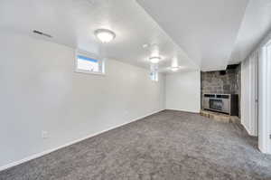 Basement featuring carpet flooring, a textured ceiling, and a fireplace