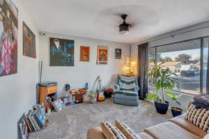 Living room with a textured ceiling, ceiling fan, and carpet