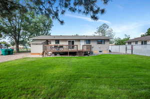 Back of property featuring a wooden deck and a yard