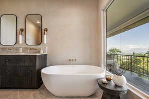 Bathroom featuring tile patterned flooring, vanity, and a tub to relax in