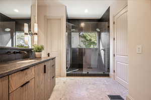 Bathroom with a shower with door, tile patterned floors, and vanity