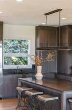 Kitchen featuring a breakfast bar, light wood-type flooring, and dark brown cabinetry