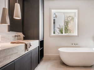 Bathroom featuring toilet, tile patterned floors, a bathing tub, and vanity