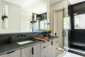 Bathroom featuring a wealth of natural light, a shower with door, vanity, and tile patterned floors