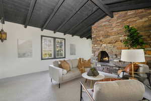 Living room with a fireplace, carpet flooring, and lofted ceiling with beams