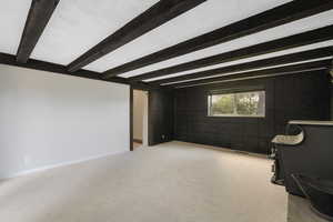 Carpeted spare room with beam ceiling