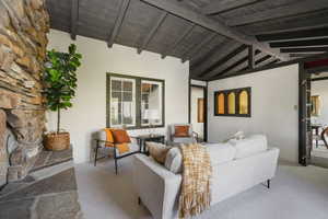 Carpeted living room with wooden ceiling, high vaulted ceiling, and beamed ceiling