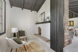 Sitting room featuring wood ceiling, carpet flooring, and vaulted ceiling with beams