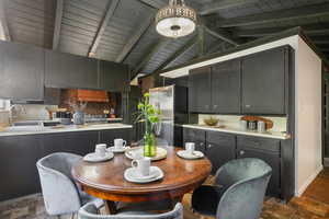 Dining area with lofted ceiling with beams, sink, dark tile patterned flooring, a notable chandelier, and wooden ceiling