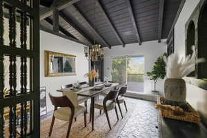 Tiled dining area with high vaulted ceiling, beam ceiling, a notable chandelier, and wood ceiling