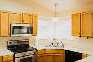 Kitchen featuring sink, lofted ceiling, pendant lighting, and stainless steel appliances