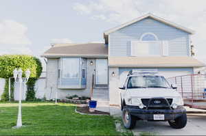 View of front facade featuring a garage and a front lawn