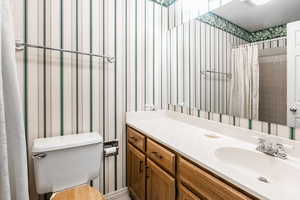 Full bath off of the second bedroom featuring toilet, vanity, and bath/shower