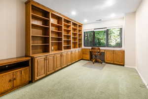 Carpeted bedroom currently being used as office space featuring built in desk