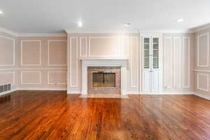 Unfurnished living room featuring ornamental molding, a high end fireplace, and wood-type flooring