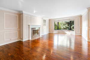 Unfurnished living room with hardwood / wood-style floors, a premium fireplace, and ornamental molding