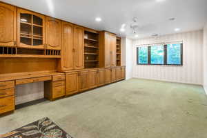 Family Room with ceiling fan, built in desk, and light carpet