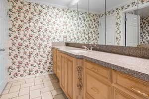 Primary Owners Bathroom with ornamental molding, tile patterned flooring, and vanity