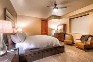 Carpeted bedroom with ceiling fan and a textured ceiling