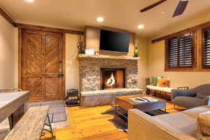 Living room featuring a fireplace, ceiling fan, and light wood-type flooring