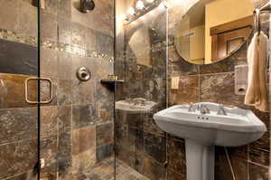 Bathroom with walk in shower and tile walls