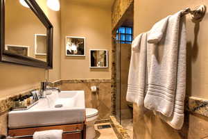 Bathroom with vanity, tile patterned floors, a shower with shower door, tile walls, and toilet